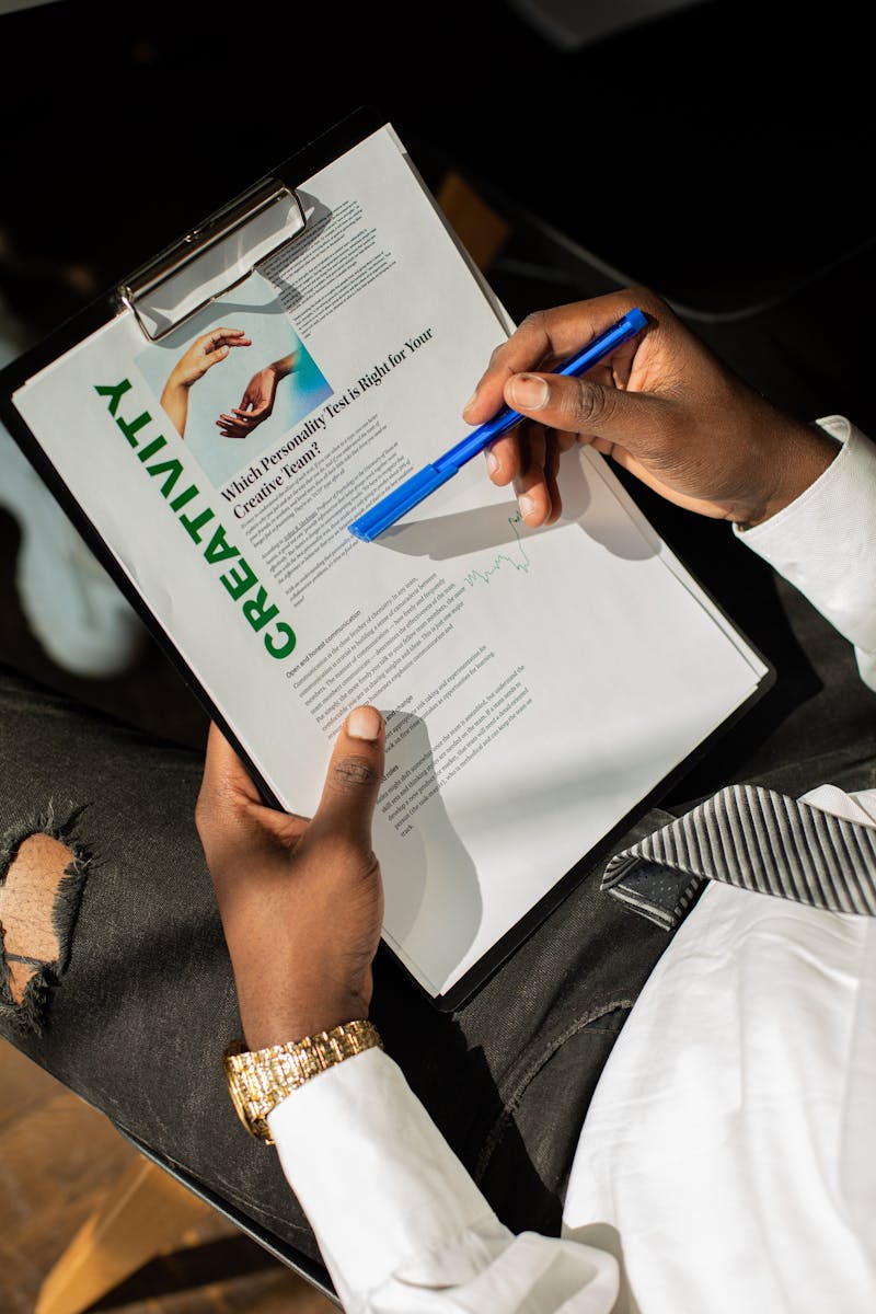 Close-up of a man reviewing a creative questionnaire with a blue pen, wearing a stylish watch.